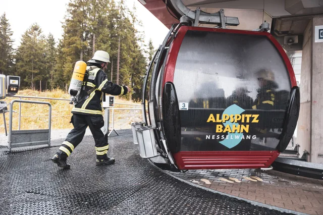Teilnehmer mit Atemschutzgeräten steigen an der Bergstation in die Gondel.