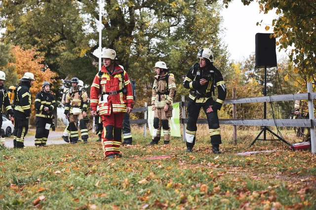 Teilnehmer in roter Einsatzkleidung und weißem Helm am Start.