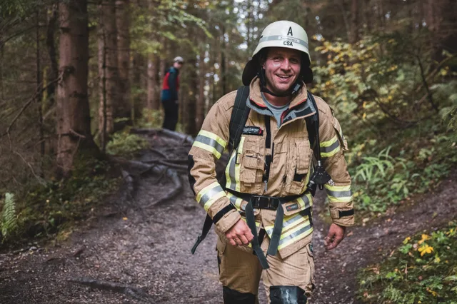 Lächelnder Teilnehmer in beiger Einsatzkleidung mit weißem Helm.