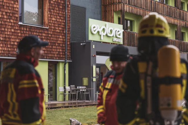 Gruppe in roter und schwarzer Einsatzkleidung vor dem Explorer Hotel.