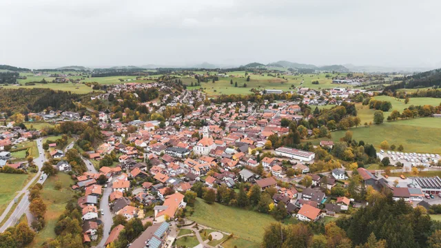 Luftaufnahme von Nesselwang mit Kirche und umliegenden Wiesen.