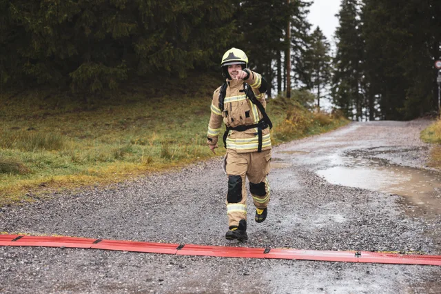Teilnehmer mit gelbem Helm und beiger Einsatzkleidung überquert die Zielmarkierung.