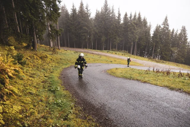 Teilnehmer in schwarzer Einsatzkleidung steigt durch eine Straßenkurve bergauf.