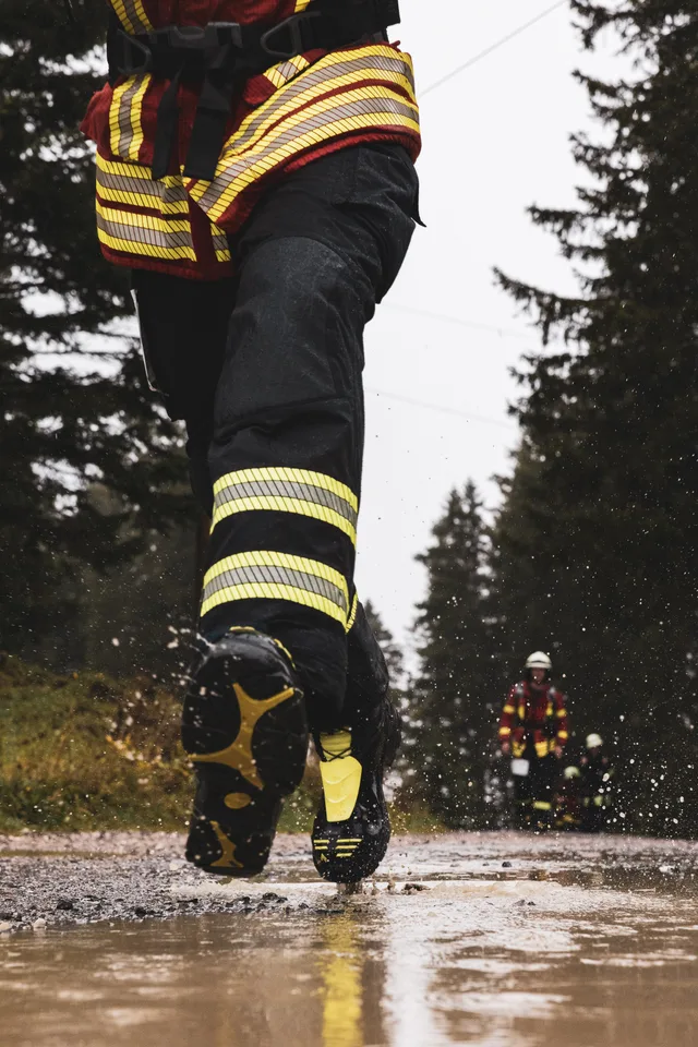 Einsatzstiefel spritzen beim Laufen Wasser aus einer Pfütze.