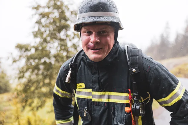 Nahansicht eines Teilnehmers mit schwarzem Helm beim Aufstieg im Regen.