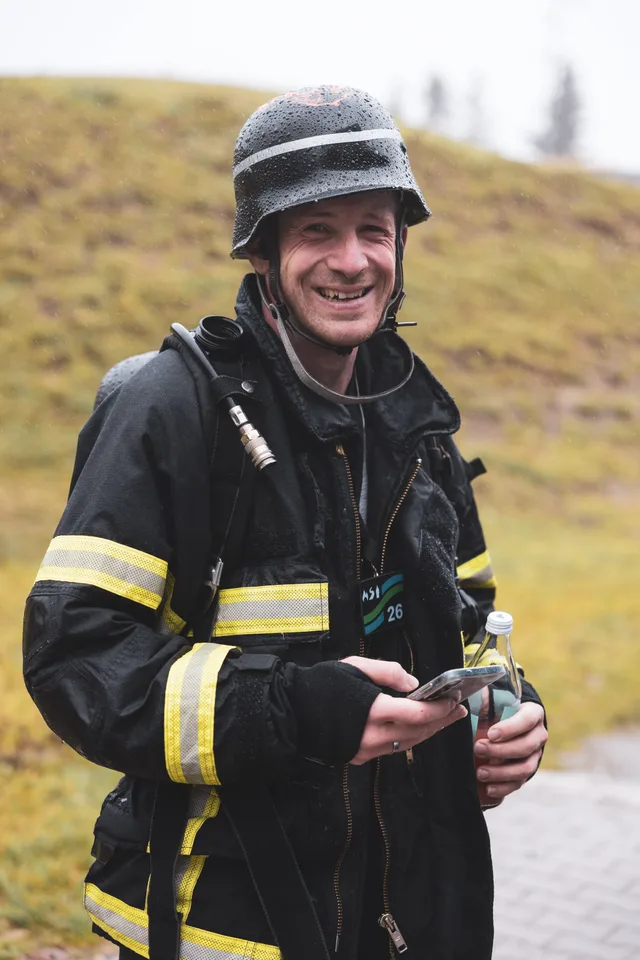 Lachender Teilnehmer mit schwarzem Helm und Getränkeflasche.
