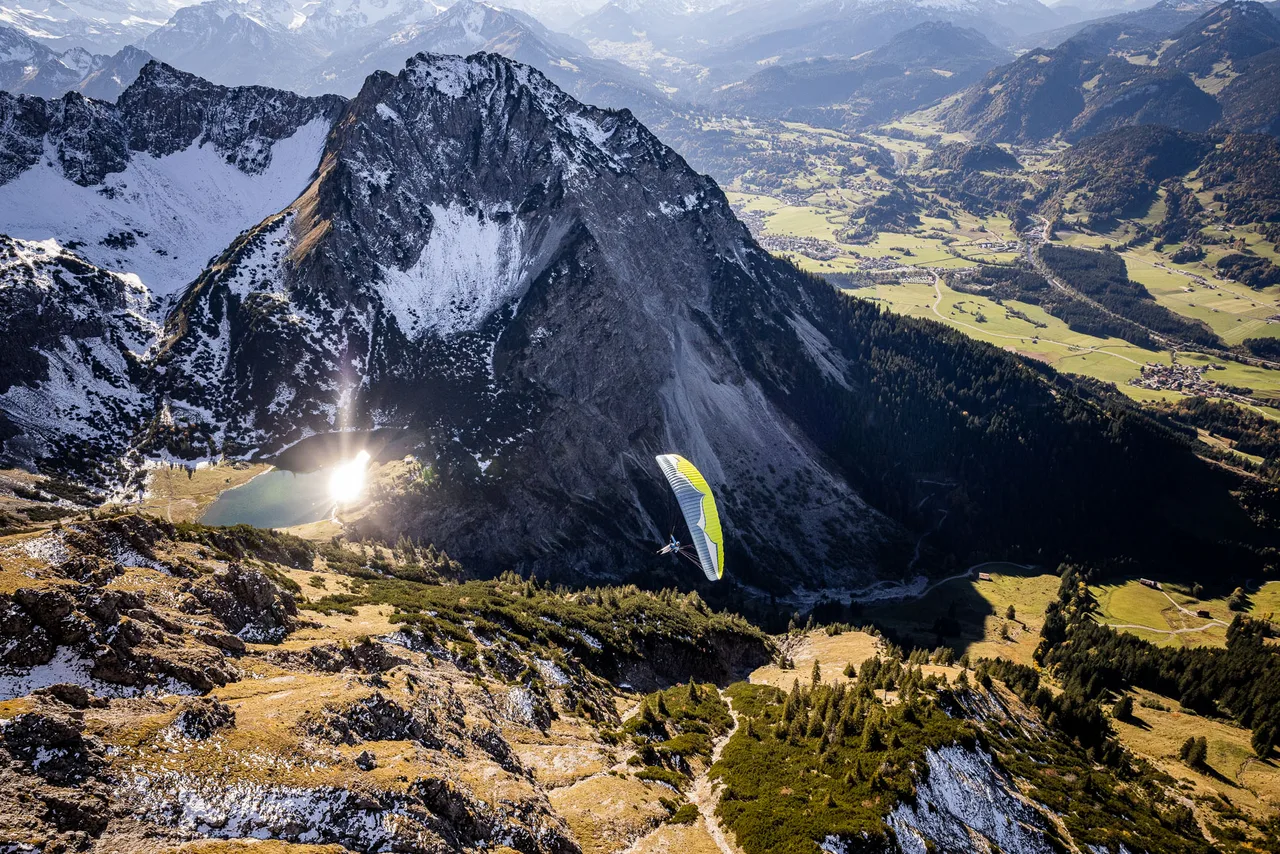 Michael Schnetzer gleitet mit dem Gleitschirm über dem Geisalpsee bei Oberstdorf im Herbstlicht.