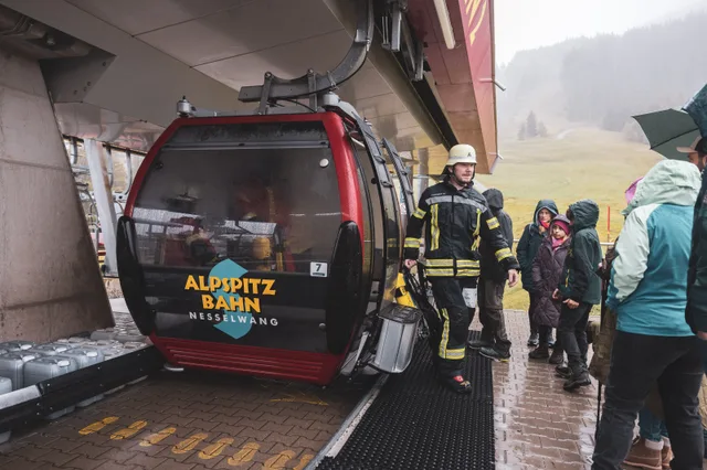 Teilnehmer in Einsatzkleidung neben der Gondel an der Bergstation.