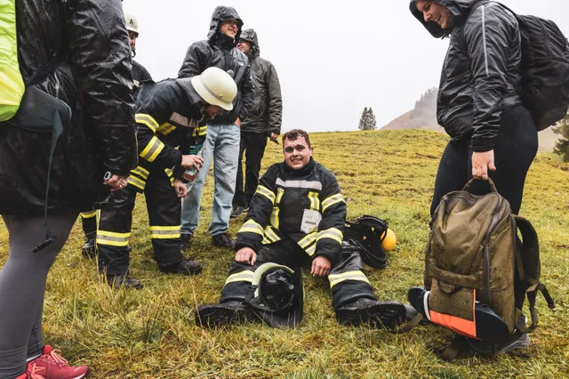 Teilnehmer sitzt im Gras, während andere ihre Ausrüstung ablegen.