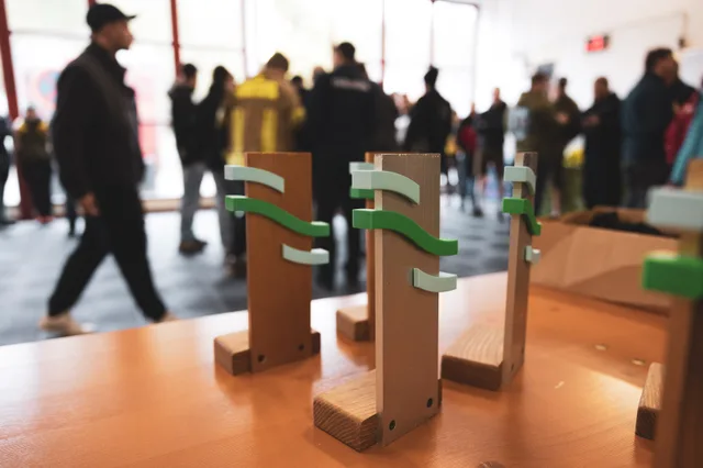 Pokale im Vordergrund und Teilnehmer im Feuerwehrhaus.