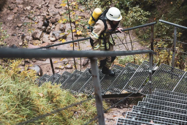 Teilnehmer in beiger Einsatzkleidung auf einer Metalltreppe, von oben gesehen.