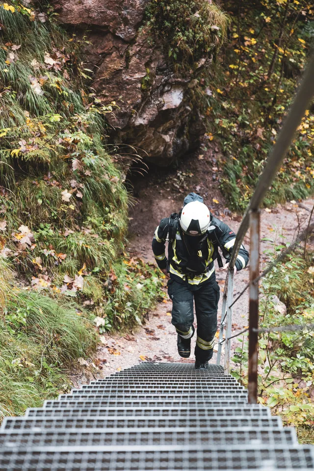 Teilnehmer in dunkler Einsatzkleidung steigt eine Metalltreppe hinauf.