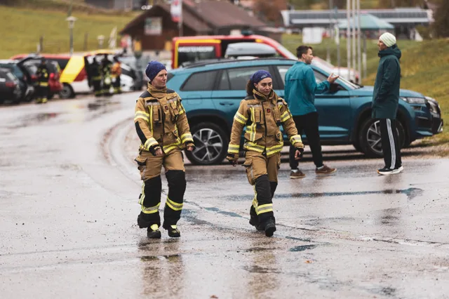 Zwei Teilnehmer in beiger Einsatzkleidung auf dem nassen Parkplatz.