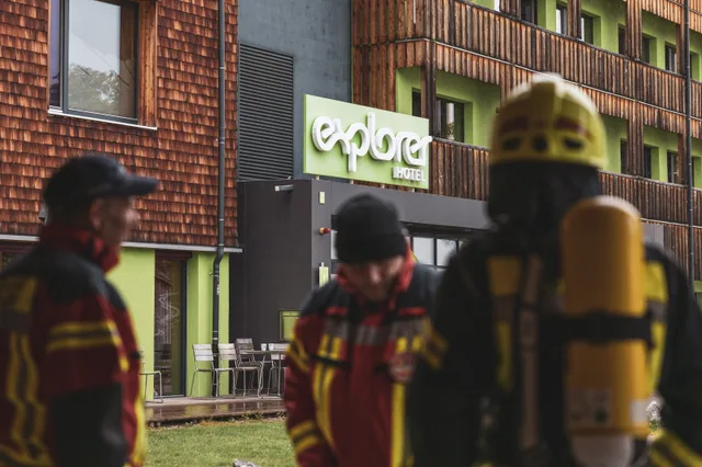 Gruppe in roter und schwarzer Einsatzkleidung vor dem Explorer Hotel.