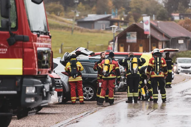 Gruppe mit Regenschirm zwischen den Fahrzeugen im Startbereich.