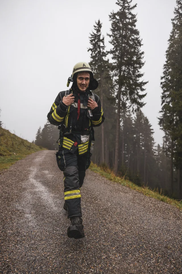 Teilnehmerin mit Atemschutzgerät auf der nassen Bergstraße am offenen Hang.