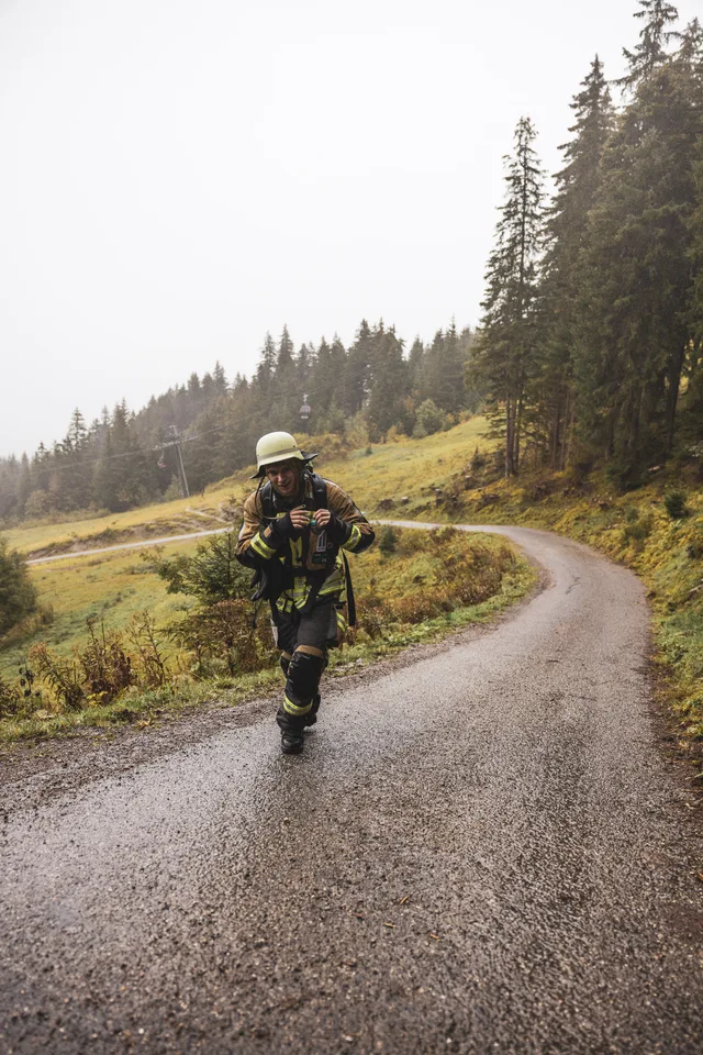 Teilnehmer mit schwarzem Helm auf der Bergstraße am Wiesenhang.