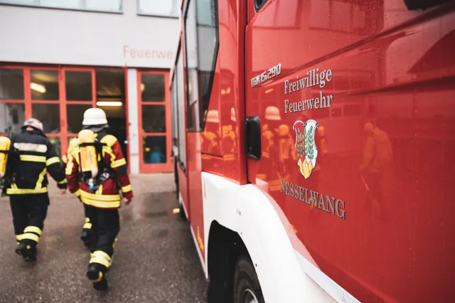 Teilnehmer gehen neben einem Feuerwehrfahrzeug zum Feuerwehrhaus.