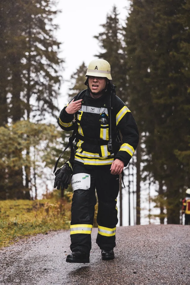 Teilnehmer in schwarzer Einsatzkleidung greift im Ziel an sein Gesicht.