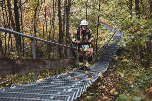 Teilnehmer in beiger Einsatzkleidung auf der langen Treppe im Herbstwald.