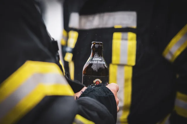 Nahansicht eines Handschuhs mit Getränkeflasche vor einer Einsatzjacke.
