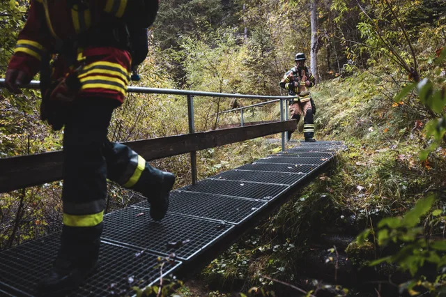 Einsatzstiefel und Hosenbeine auf einem Metallsteg im Wald.