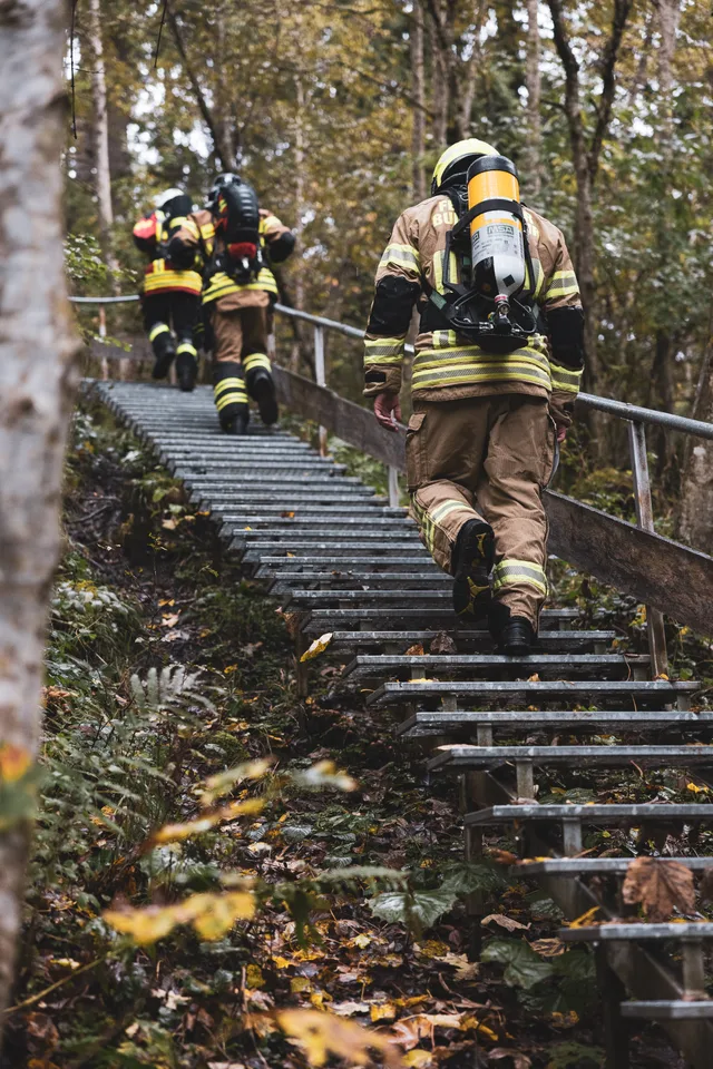 Teilnehmer mit Atemschutzgeräten von hinten auf einer steilen Waldtreppe.