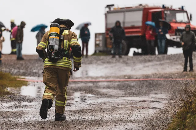 Teilnehmer in beiger Einsatzkleidung läuft auf dem Schotter zum Feuerwehrfahrzeug.