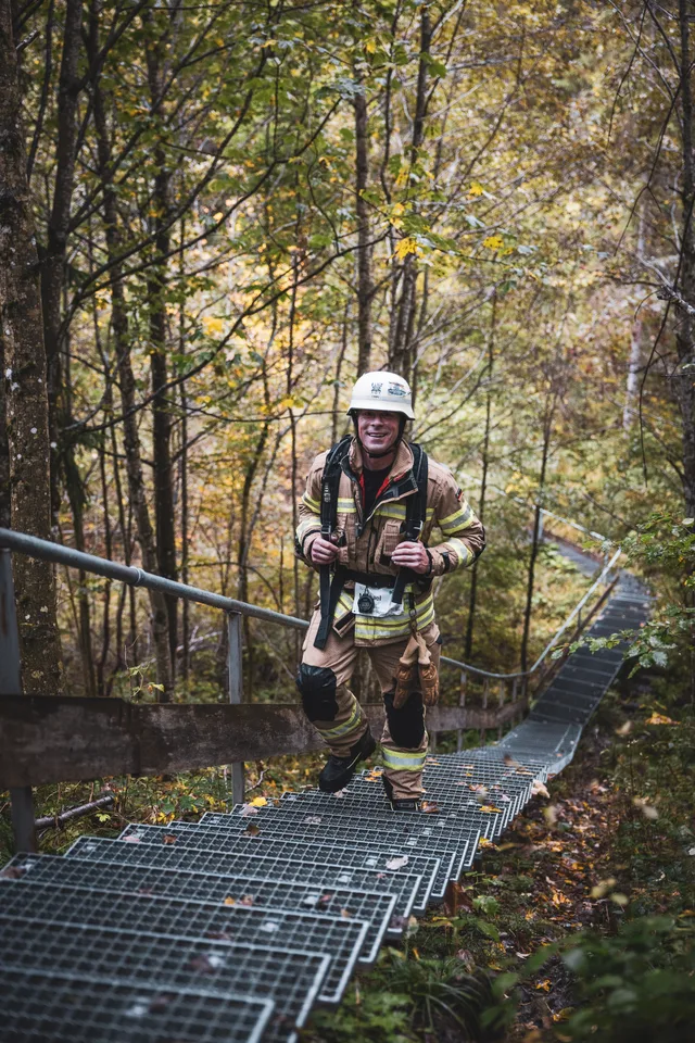 Teilnehmer in beiger Einsatzkleidung auf der langen Treppe im Herbstwald.