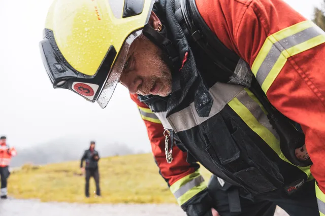 Teilnehmer mit gelbem Helm und roter Einsatzkleidung beugt sich nach vorn.