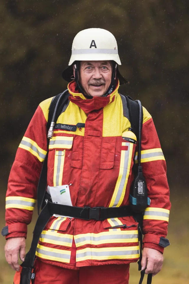 Teilnehmer mit weißem Helm und roter Einsatzkleidung zeigt den Daumen nach oben.