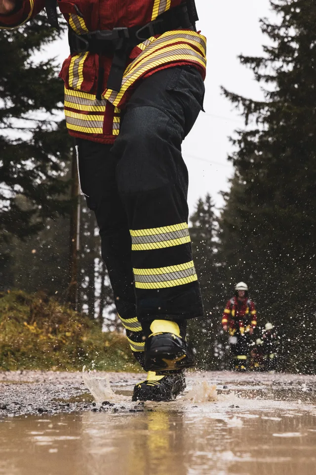 Einsatzstiefel spritzen beim Laufen Wasser aus einer Pfütze.