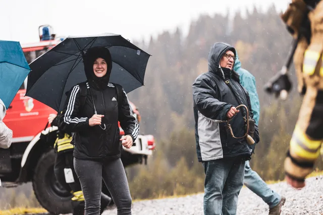 Zuschauer unter Regenschirmen am Rand des Zielbereichs.