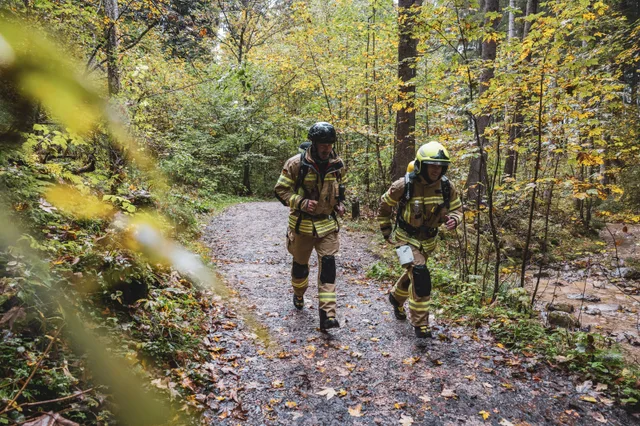 Zwei Teilnehmer in beiger Einsatzkleidung auf einem Waldweg.