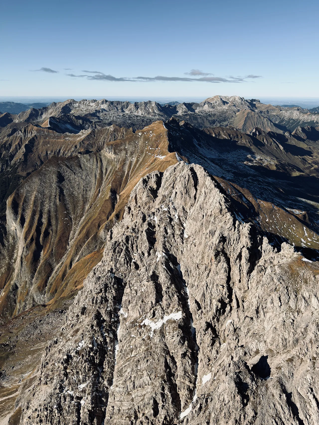 Felsgrat des Großen Wilden aus der Luft vor goldbraunen Berghängen und schattigen Flanken mit Schneeresten