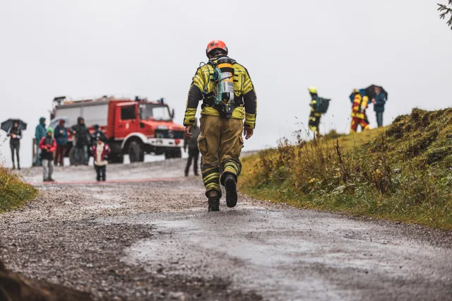 Teilnehmer mit orangefarbenem Helm läuft von hinten gesehen zum Ziel am Feuerwehrfahrzeug.