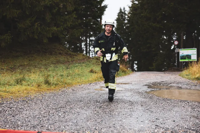 Teilnehmer in schwarzer Einsatzkleidung überquert die rote Zielmarkierung.
