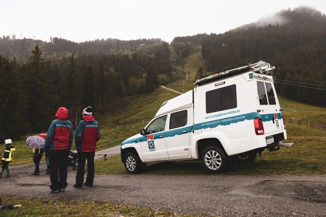 Helfer und Rettungsfahrzeug am Rand der Bergstraße.