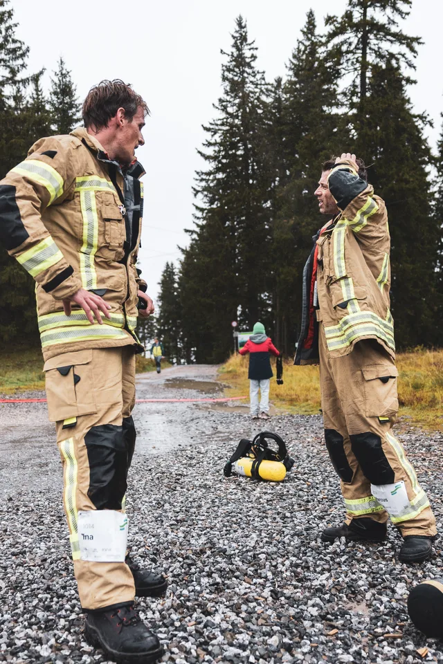 Teilnehmer in beiger Einsatzkleidung stehen mit abgelegter Ausrüstung im Zielbereich.