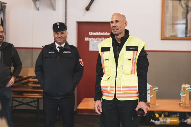 Organisator in Warnweste spricht neben einem uniformierten Feuerwehrmann.