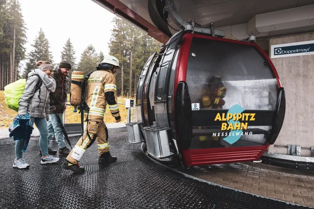 Teilnehmer in beiger Einsatzkleidung steigen in die Gondel.