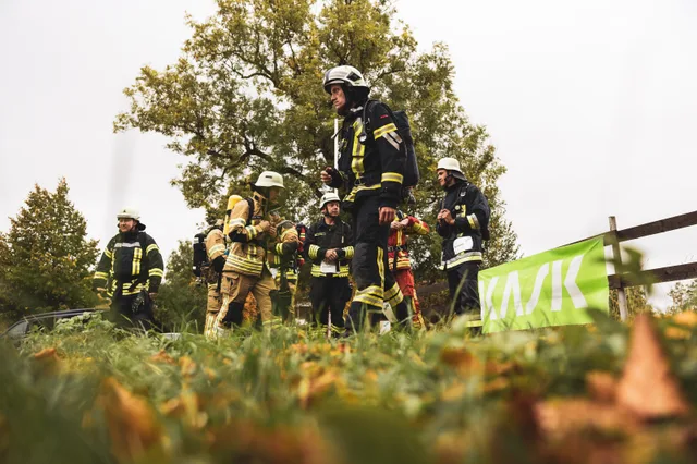 Ein Feuerwehrmann setzt sich vor wartenden Teilnehmern und einem grünen Banner in Bewegung.