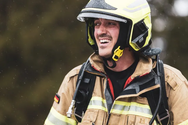 Lachender Teilnehmer mit gelbem Helm im Zielbereich.