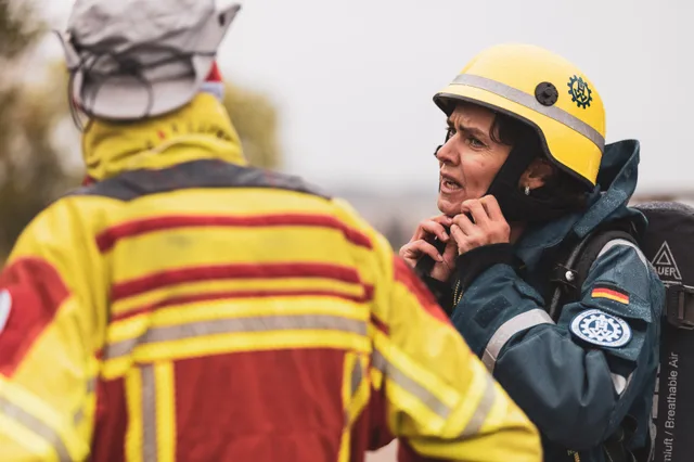 Teilnehmerin mit gelbem Helm richtet ihren Kinnriemen.