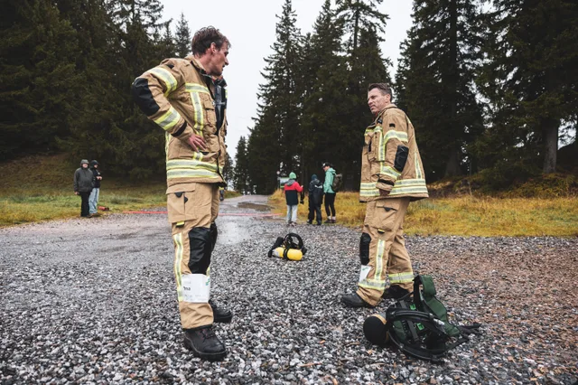 Teilnehmer in beiger Einsatzkleidung stehen mit abgelegter Ausrüstung im Zielbereich.