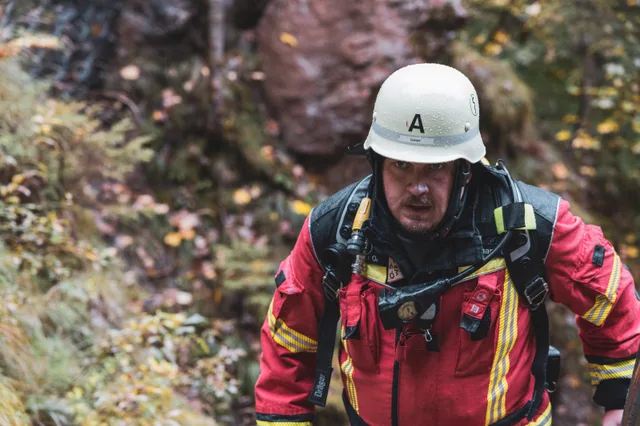 Nahansicht eines Teilnehmers in roter Einsatzkleidung auf der Waldtreppe.