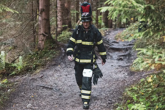 Teilnehmer in schwarzer Einsatzkleidung und dunklem Helm im Wald.