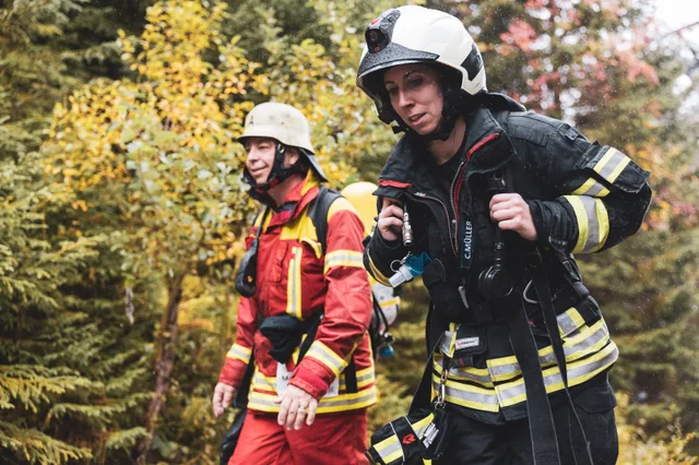 Zwei Teilnehmer in roter und schwarzer Einsatzkleidung auf der Bergstraße.