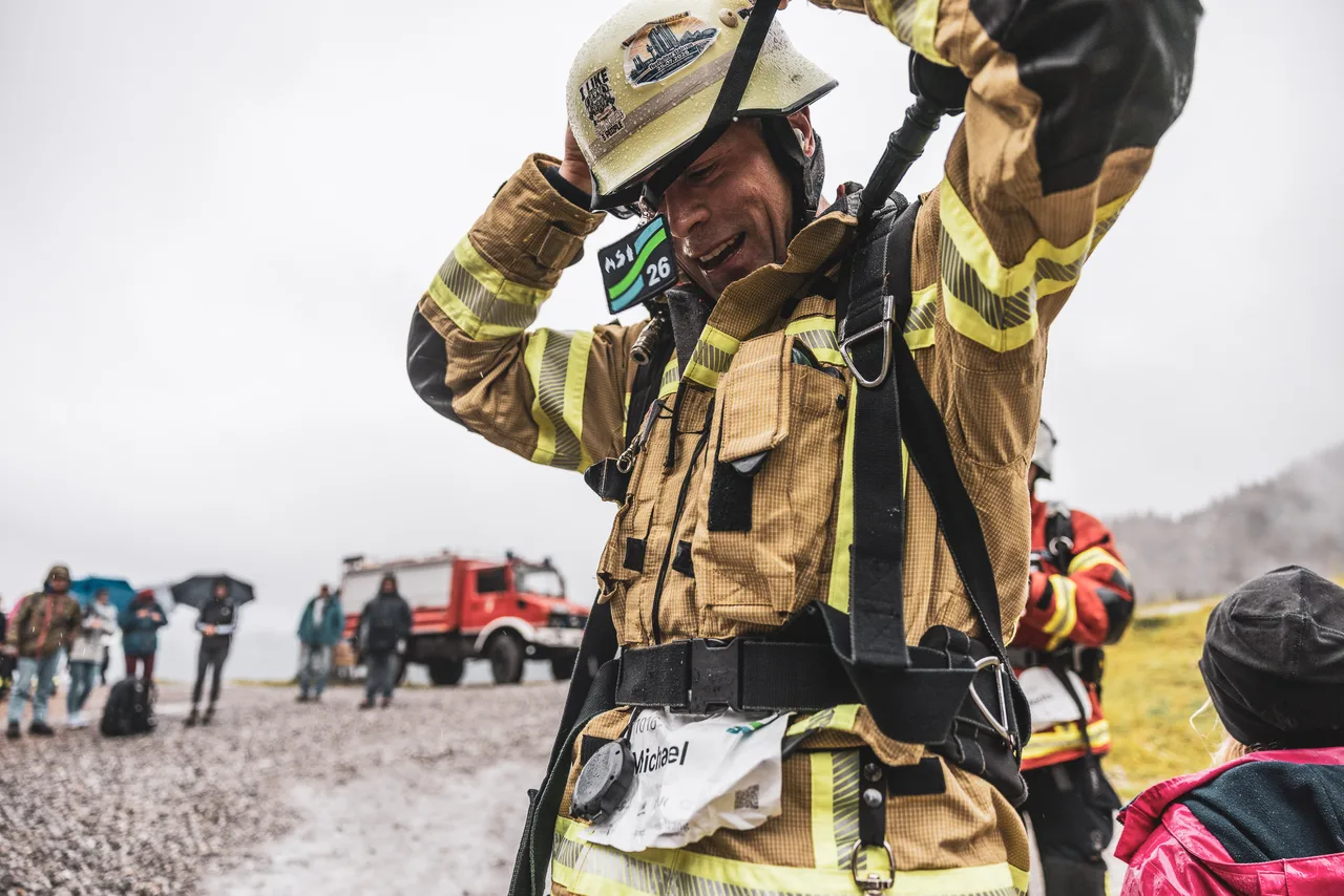 Feuerwehrteilnehmer zieht das Band seiner Medaille über den Helm; auf seiner Startnummer steht Michael.