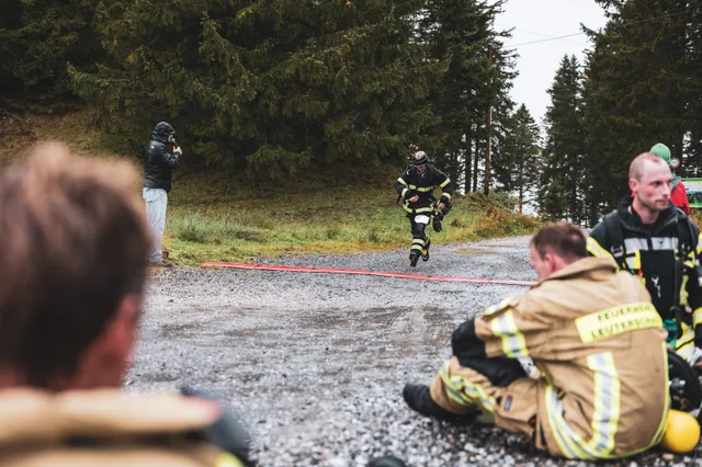 Teilnehmer läuft ins Ziel, während andere auf dem Schotter sitzen.